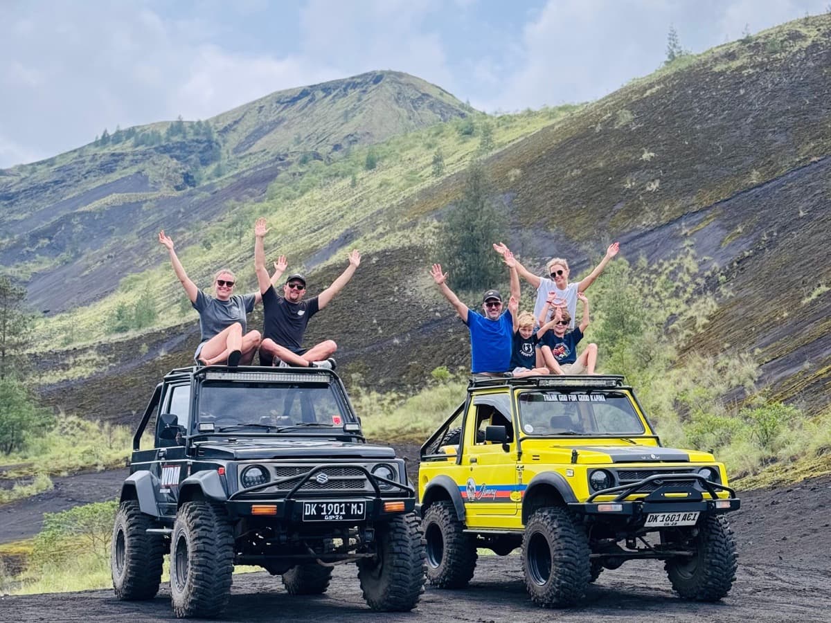 Travellers cheering atop classic 4x4 jeeps at Mount Batur