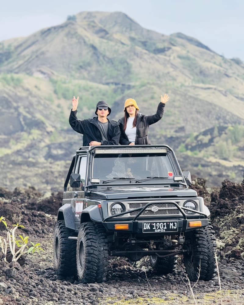 Couple waving from an open 4x4 jeep on the black lava fields