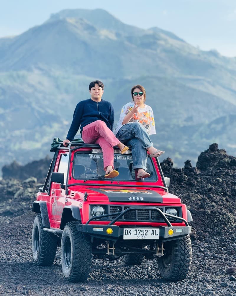 Travellers perched on a red 4x4 jeep at the volcano