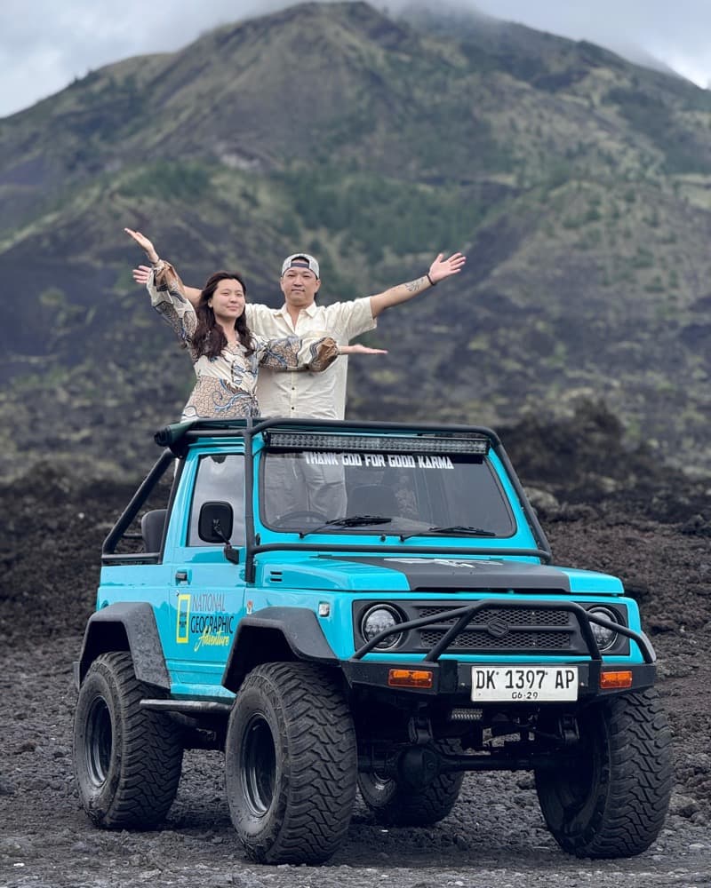 Couple standing in a turquoise jeep before the volcano