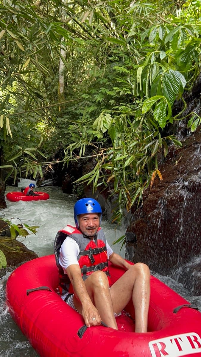 A rider relaxes in the tube in a lush green canyon by a small waterfall
