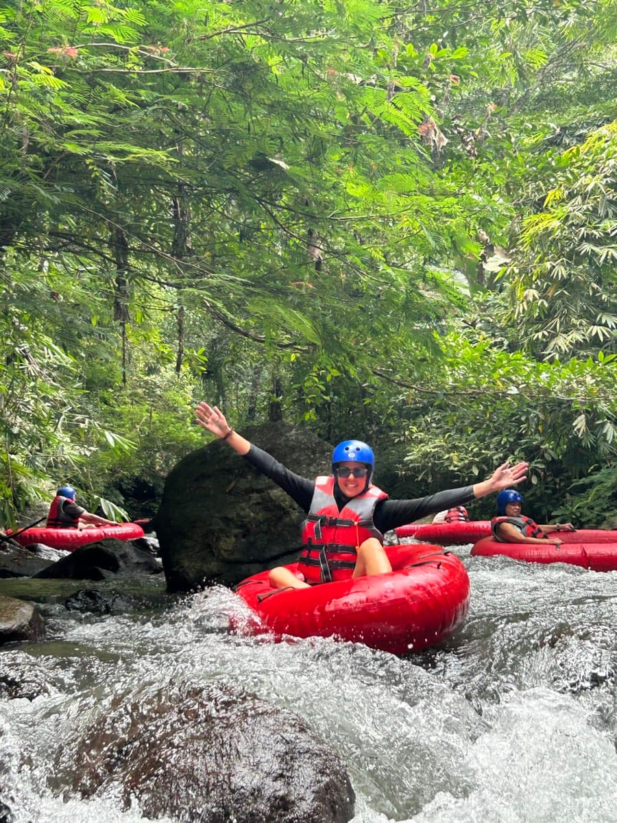 A rider raises an arm dropping into a rapid with friends behind