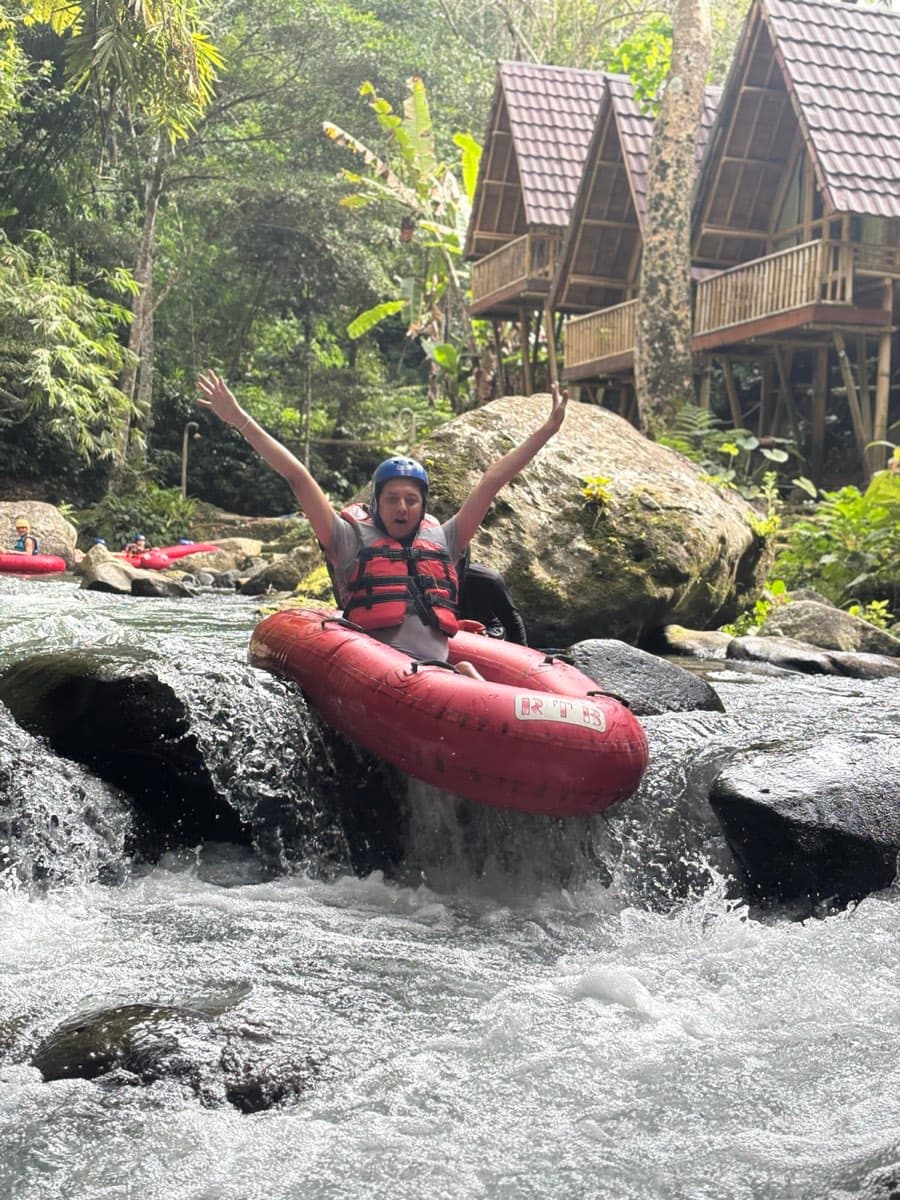 A rider throws both arms up sliding down a small drop by the lodges