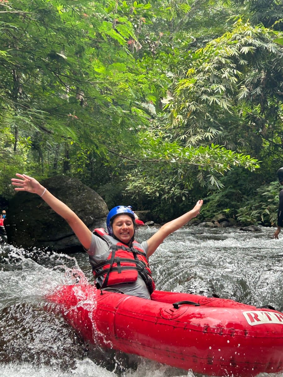 A rider throws her arms wide as the tube hits a splashing rapid