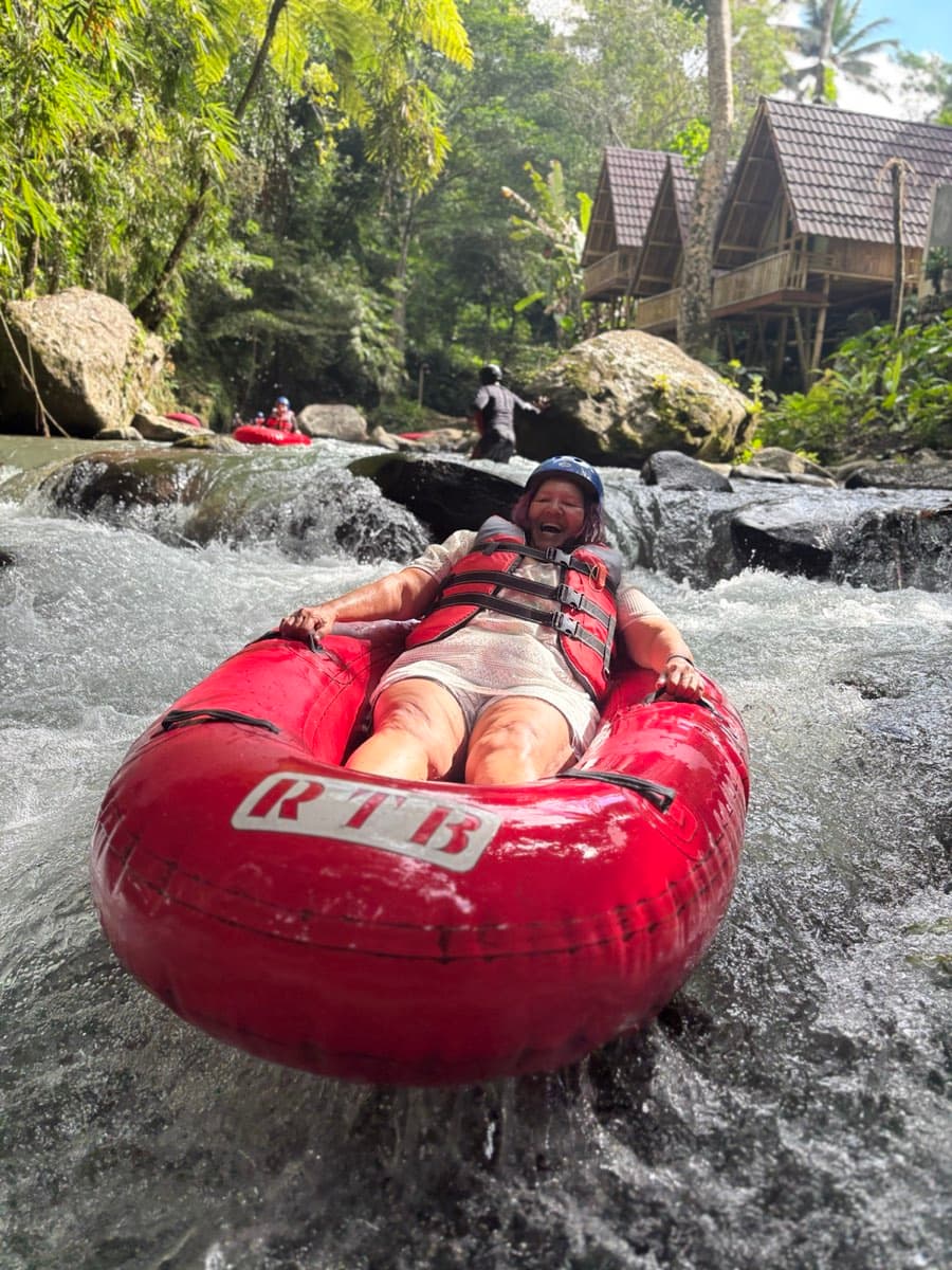 A rider reclines laughing in the tube below the bamboo huts
